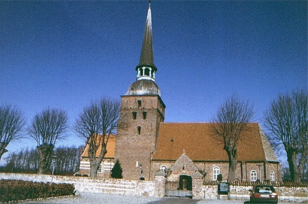 Nahansicht des spitzen Laternenturms von Kippinge Kirke mit Eingangsvorbau und Friedhofsmauer