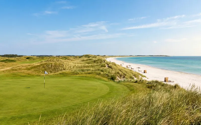 Greenfairway direkt am hellen Sandstrand mit Strandkörben und Ostsee — Golfen und Strandurlaub in einem Bild