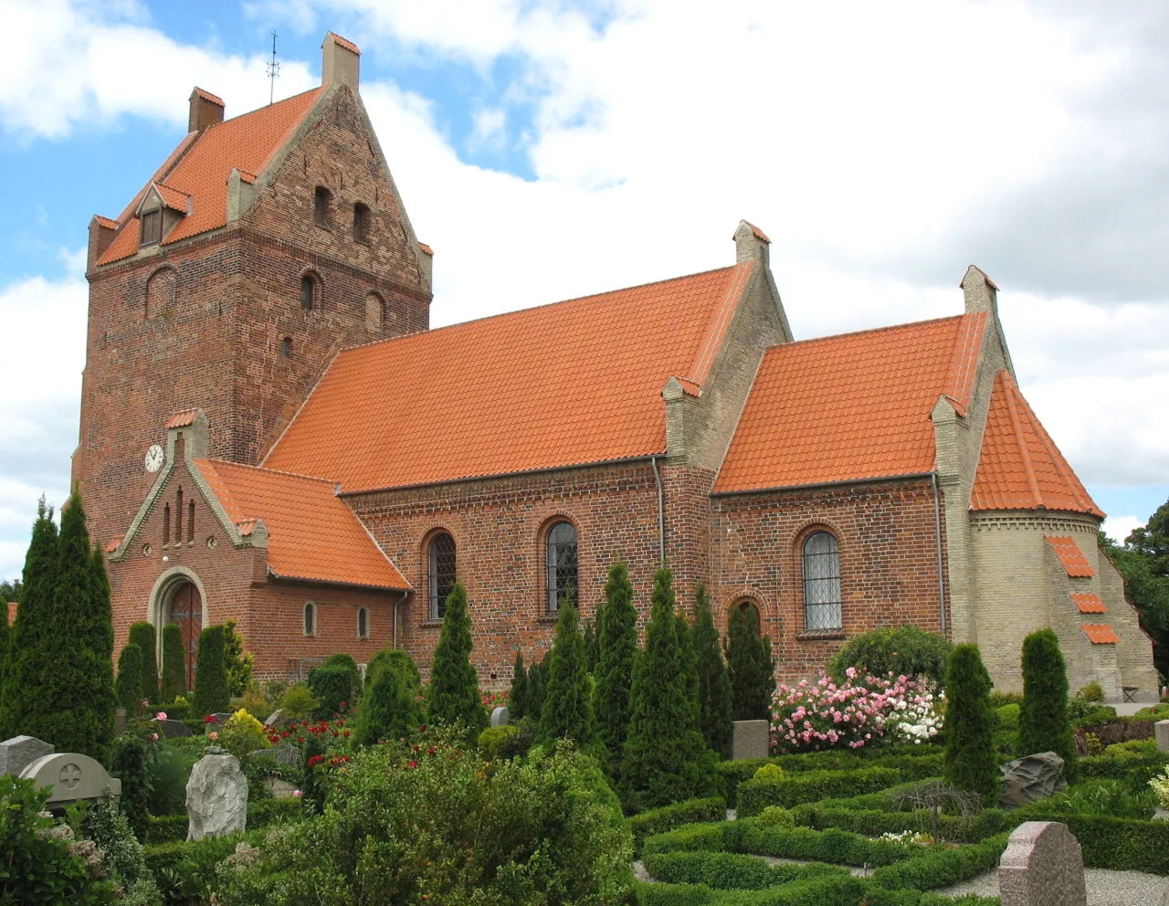 Væggerløse Kirke: mittelalterliche rote Backsteinkirche mit Treppengiebel-Turm und gepflegtem Friedhof mit niedrigen Buchsbaumhecken