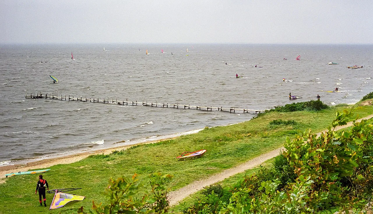 Windsurfer mit bunten Segeln auf der dänischen Küste, Blick von der Düne über Strand und Meer